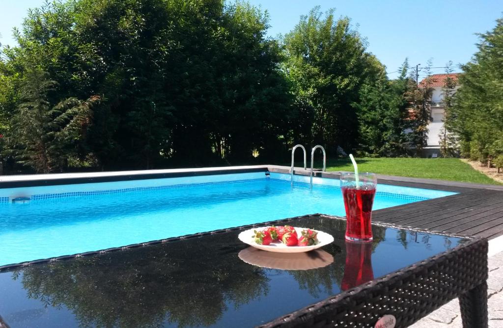 a drink and a bowl of fruit on a table next to a pool at Equinaturi in Santo Tirso