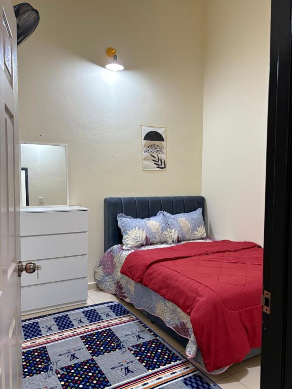 a bedroom with a bed with a red blanket and a mirror at Arora Homestay in Marang