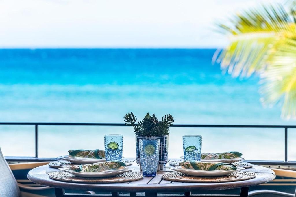 a table with plates of food and a view of the ocean at Kulakane 310 · KK 310 Updated BeachFront 2BD w AC Pool in Kahana