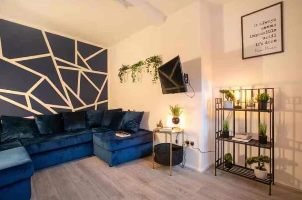 ein Wohnzimmer mit einem blauen Sofa und einigen Pflanzen in der Unterkunft Base is a lovely place to unwind after a long day in Wincobank