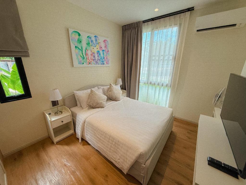 a bedroom with a white bed and a window at FAMILY HOMES HALO, brand new 2-bedroom Apartment with Pool Access in Phuket