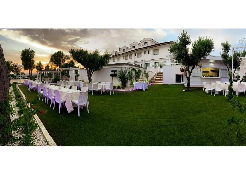 a lawn with white tables and chairs in front of a building at Hotel Paradiso in Collina in San Giovanni Rotondo