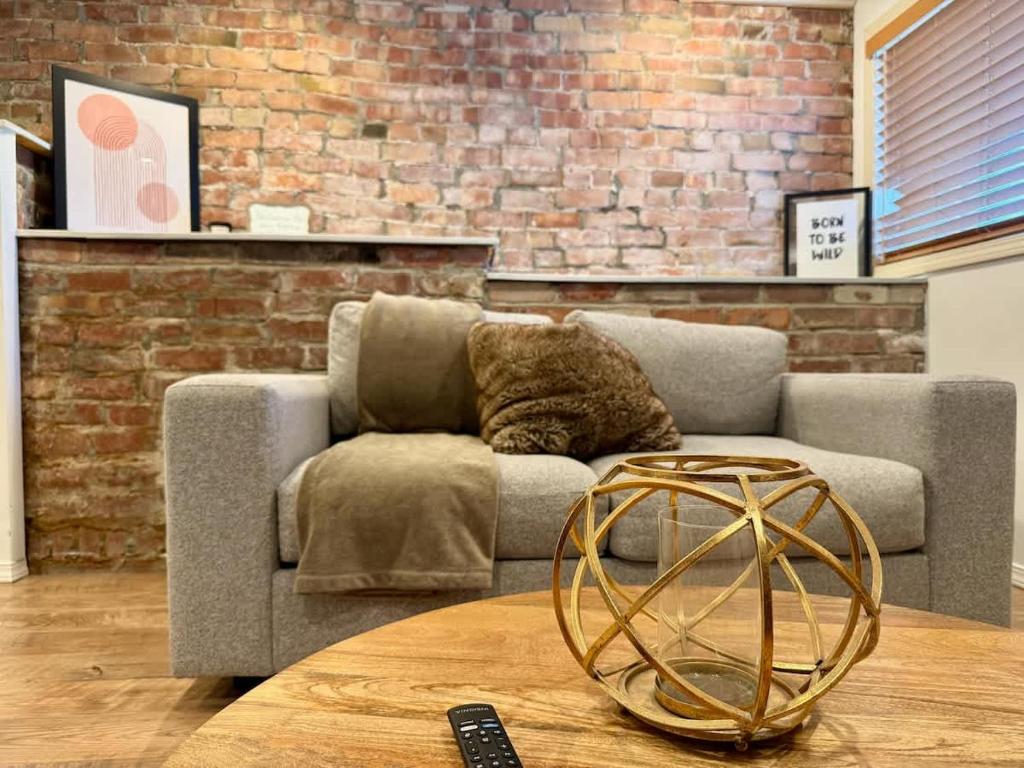 a living room with a couch and a brick wall at Charming Marmalade Flat in Downtown Salt Lake City in Salt Lake City