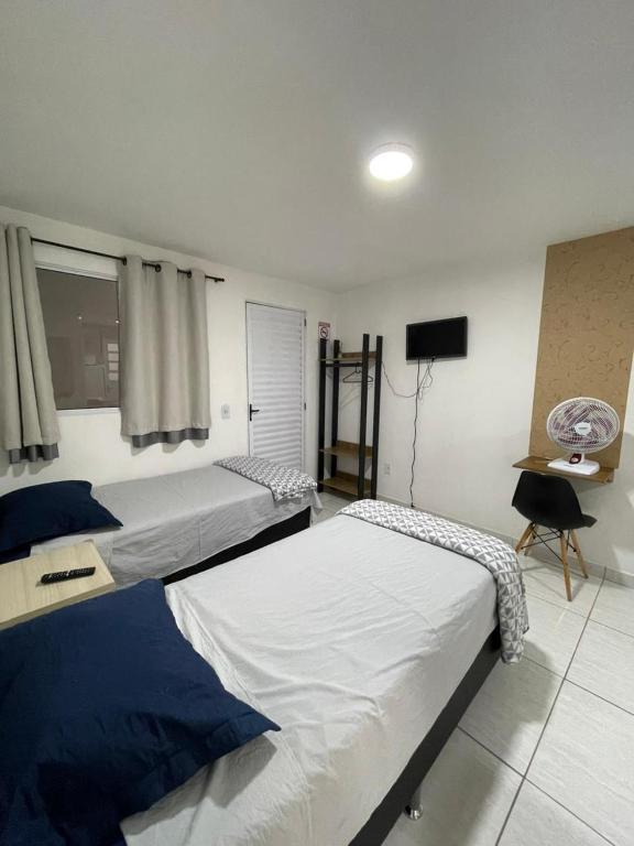 a bedroom with two beds and a television in it at Studio 107 in Sao Paulo