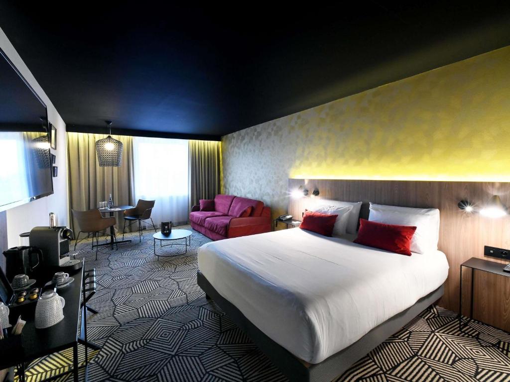 a bedroom with a large bed and a living room at Mercure Arras Centre Gare in Arras
