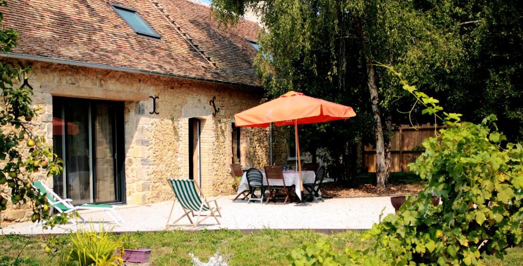 a patio with two chairs and an orange umbrella at Gîte 'Le 31' in Coulaines