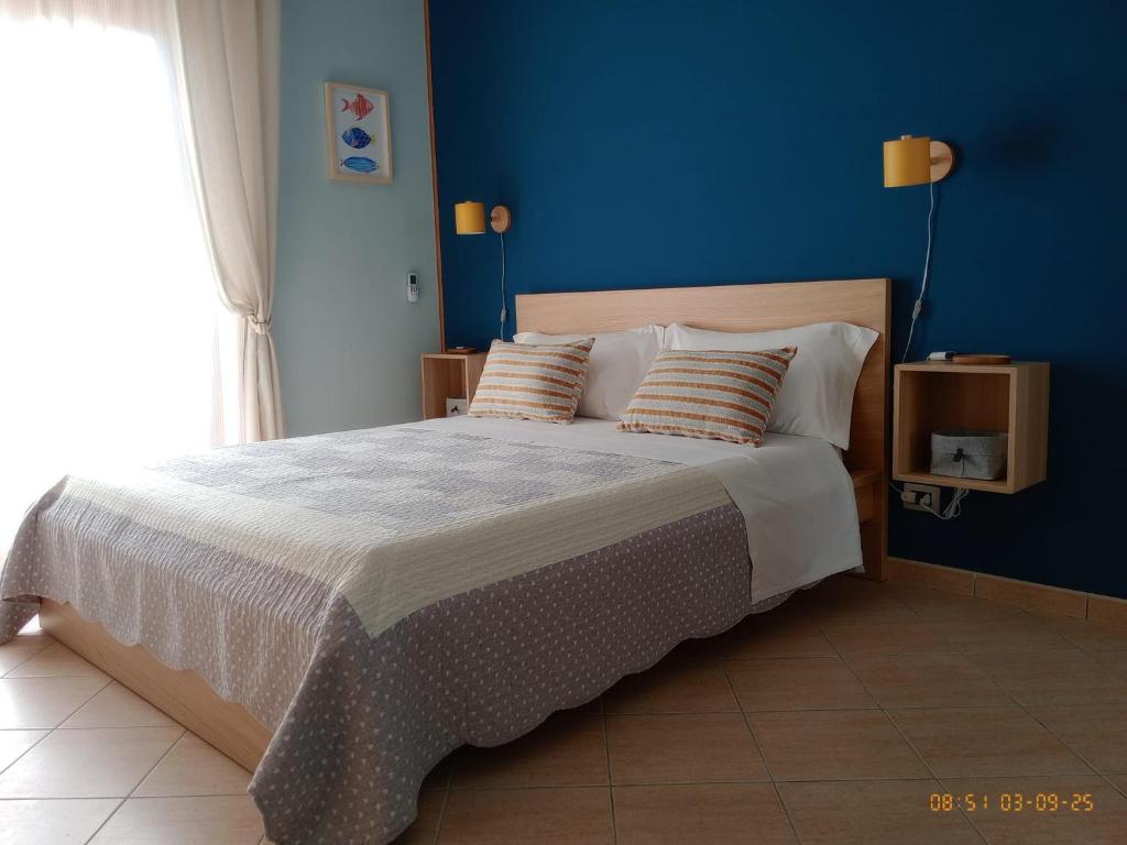 a bedroom with a large bed with a blue wall at The Way of the Tower in Isola Sacra