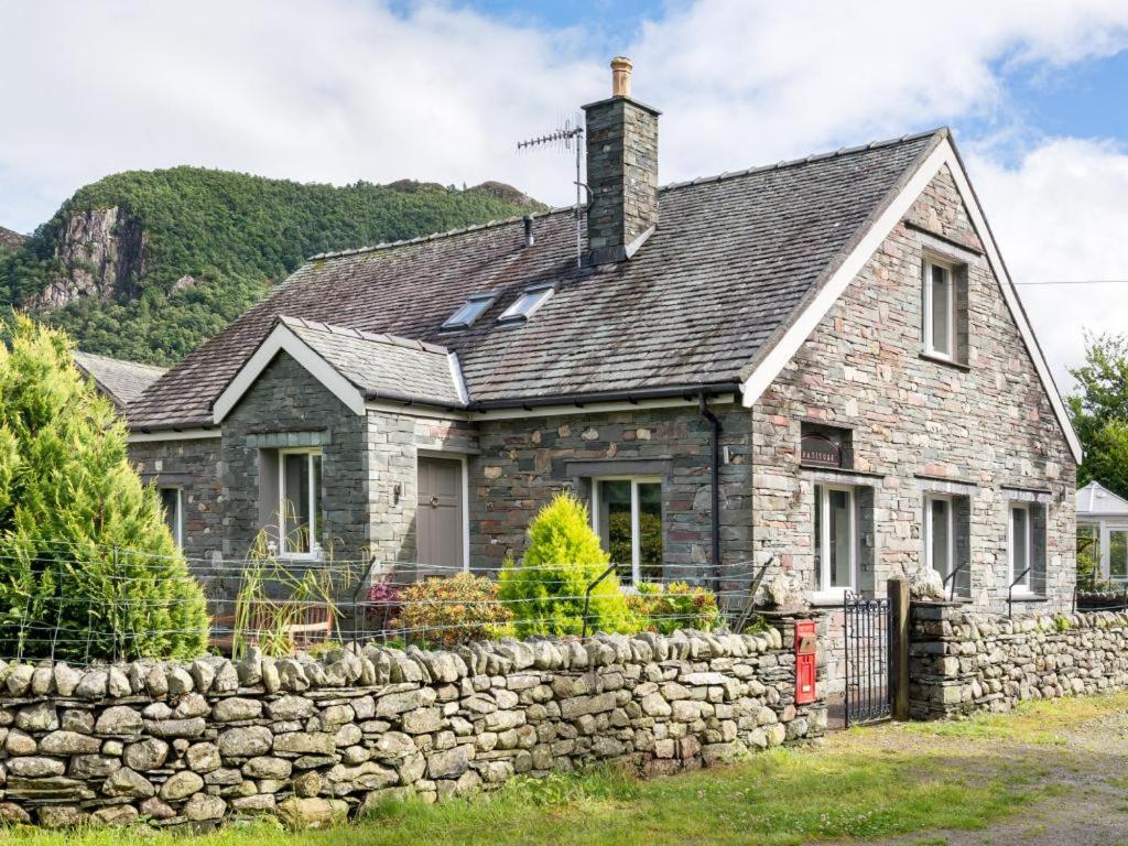 una antigua casa de piedra con un muro de piedra en 4 Bed in Borrowdale SZ219, en Grange