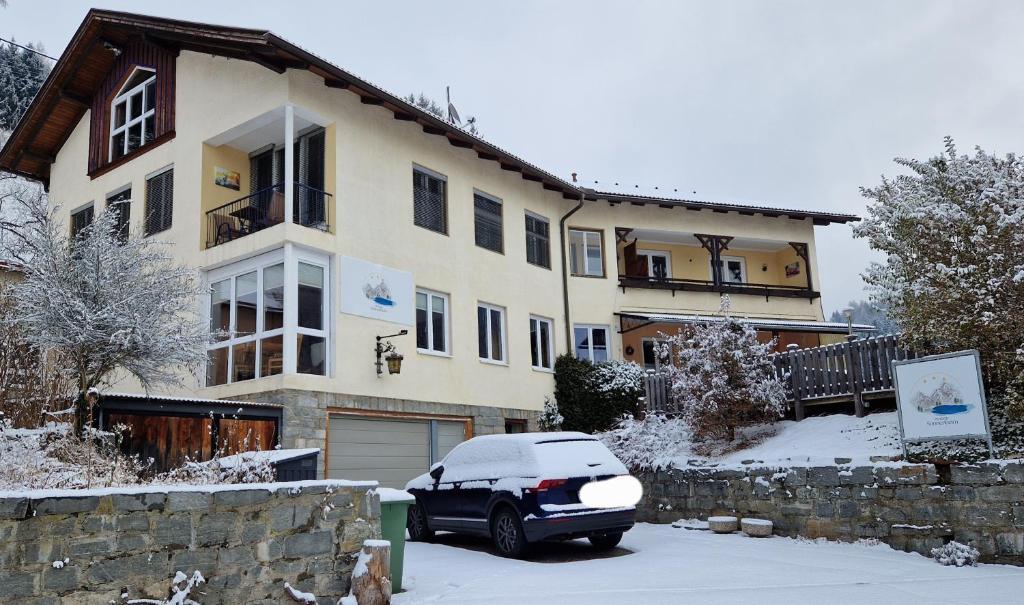 a car parked in front of a house in the snow at Pension Sonnenheim in Gmünd in Kärnten