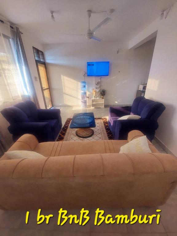 a living room with a large brown couch and chairs at Ekebute BnB in Mombasa