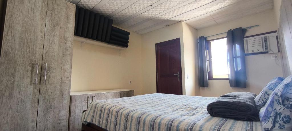 a bedroom with a bed and a window at Casa com garagem no coração de Arraial! in Arraial do Cabo