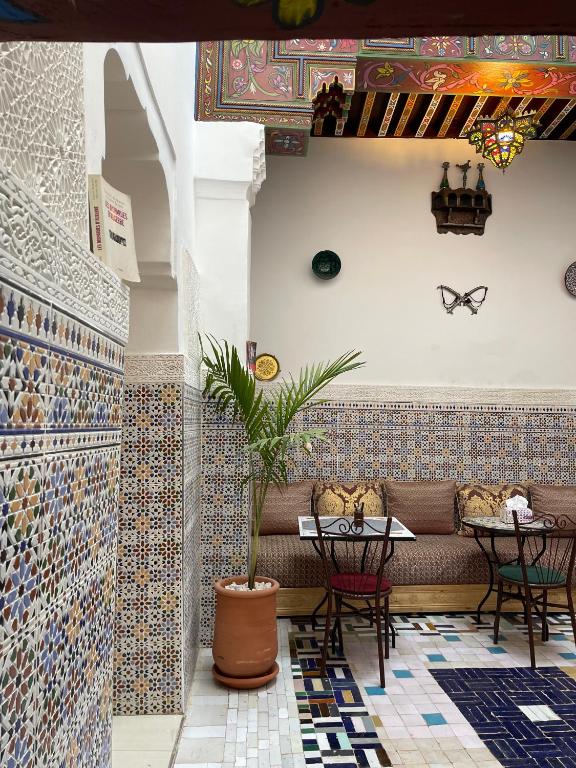 a restaurant with a couch and tables and tiles at Riad la Mentha in Fès