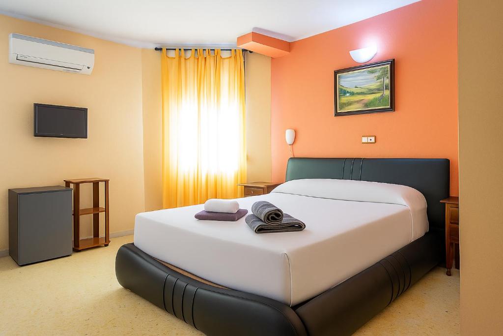 sypialnia z dużym białym łóżkiem z pomarańczowymi ścianami w obiekcie Hotel Velis w mieście Vélez-Málaga