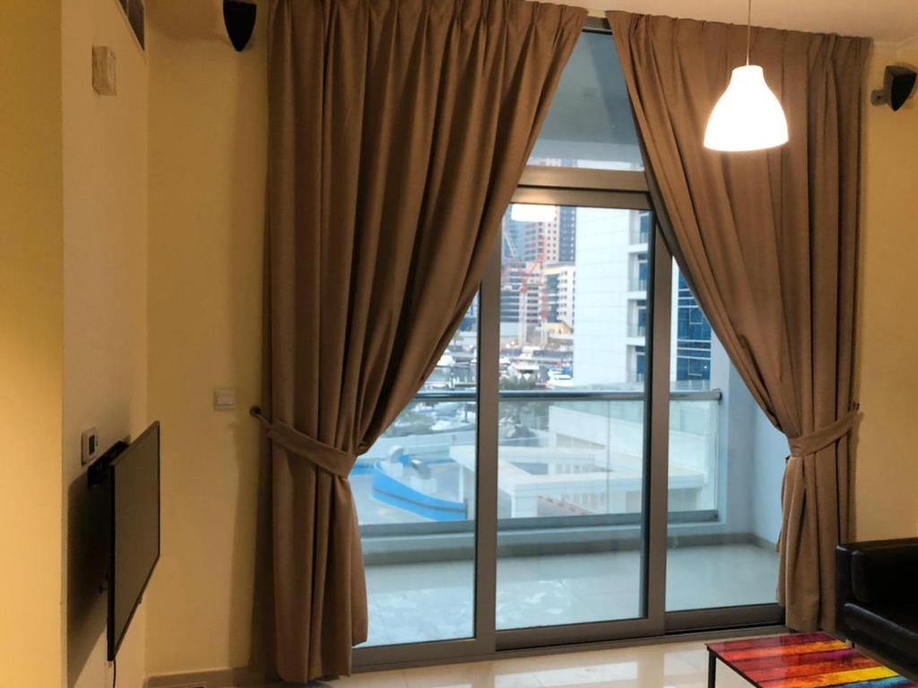 アブダビにあるPerfecto Studio Apartmentsのリビングルーム(カーテン付きの大きな窓付)