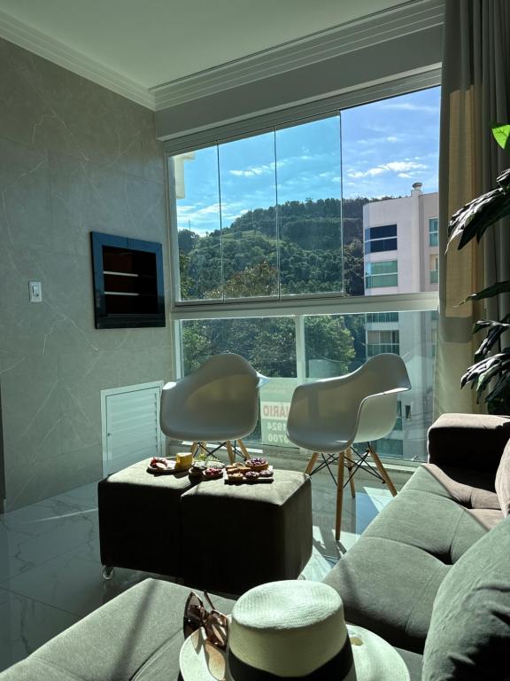 a living room with a couch and chairs and a large window at Apto das Tulipas- 2 Quartos, Apto todo climatizado - à 150m do Parque Termal! in Piratuba