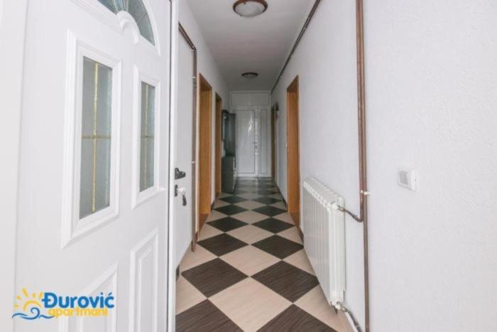 a hallway with a checkered floor in a house at Apartmani Djurovic in Dobra Voda