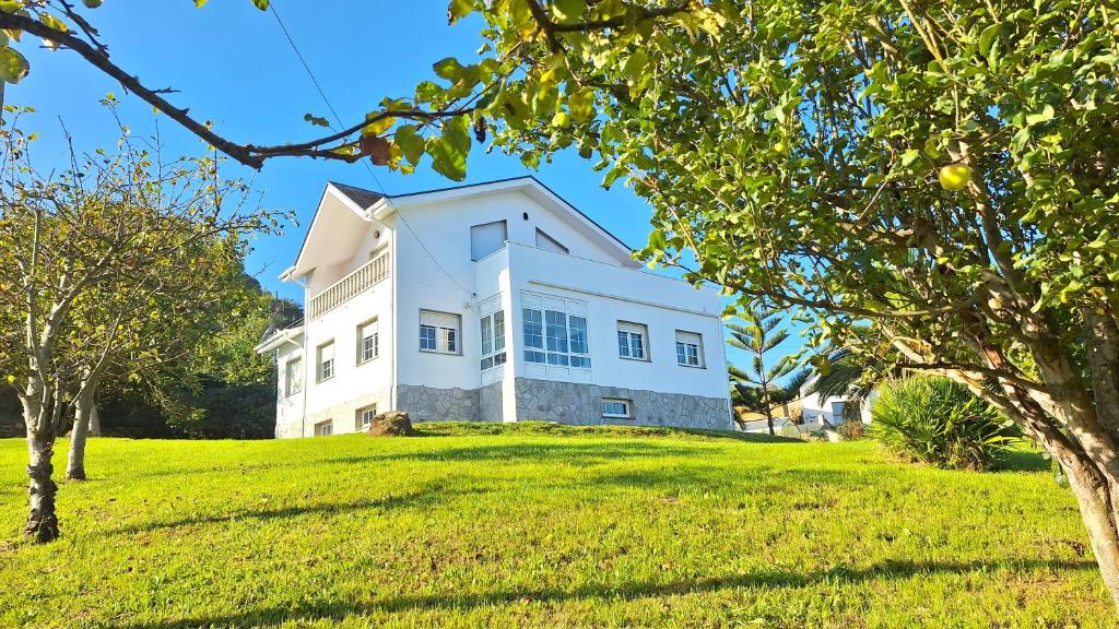 a white house on a grassy hill with trees at Casa Naveira vistas mar en Foz in Foz