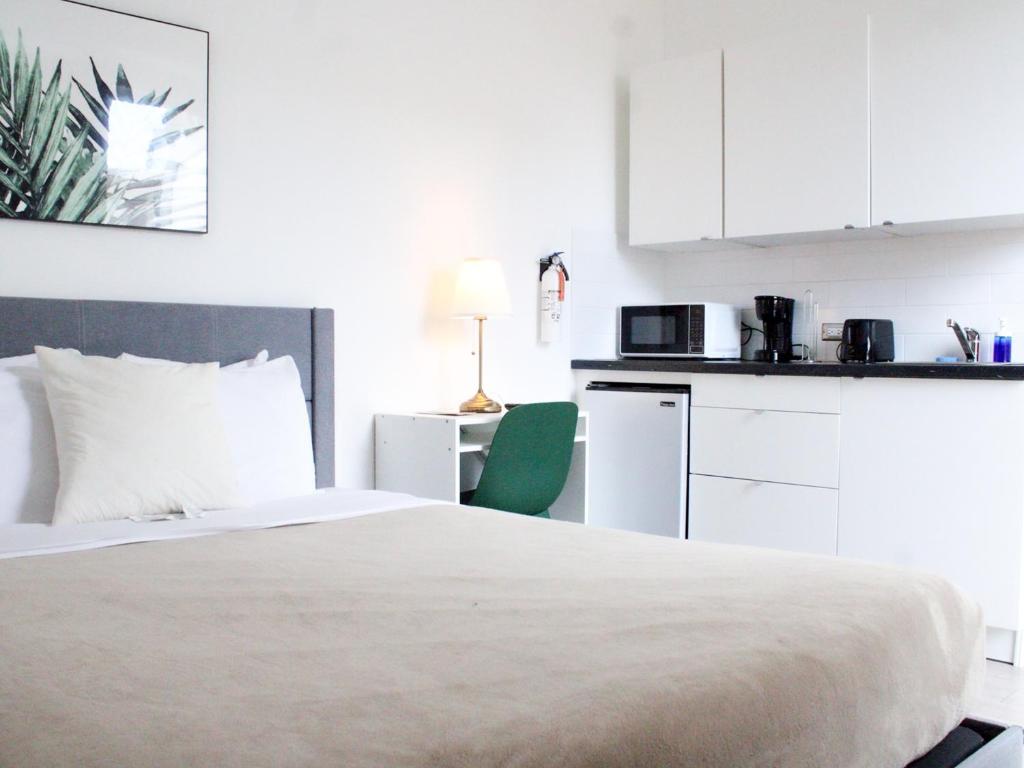 Un dormitorio blanco con una cama y una cocina. en Villas at Auxilio Mutuo 106, en San Juan