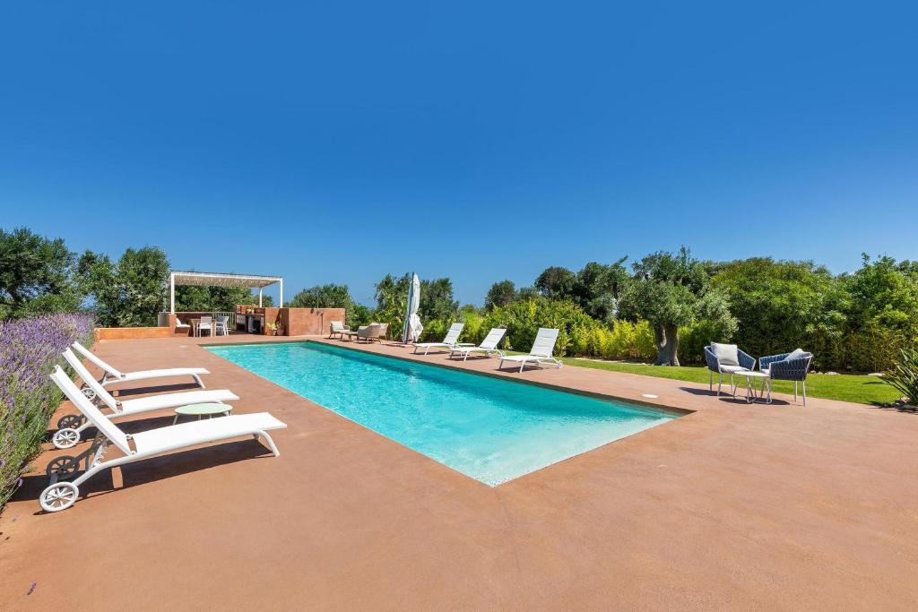 - une piscine entourée de chaises longues et de chaises longues dans l'établissement Villa Malusida by Perle di Puglia, à Carovigno