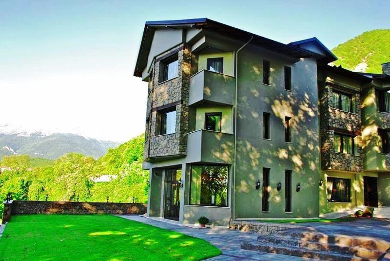 a large house with a green lawn in front of it at Melies Boutique Hotel in Kato Loutraki