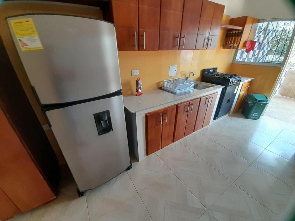 une cuisine avec un réfrigérateur en acier inoxydable et des armoires en bois dans l'établissement Bonito Apartamento en Mompox, à Santa Cruz de Mompox