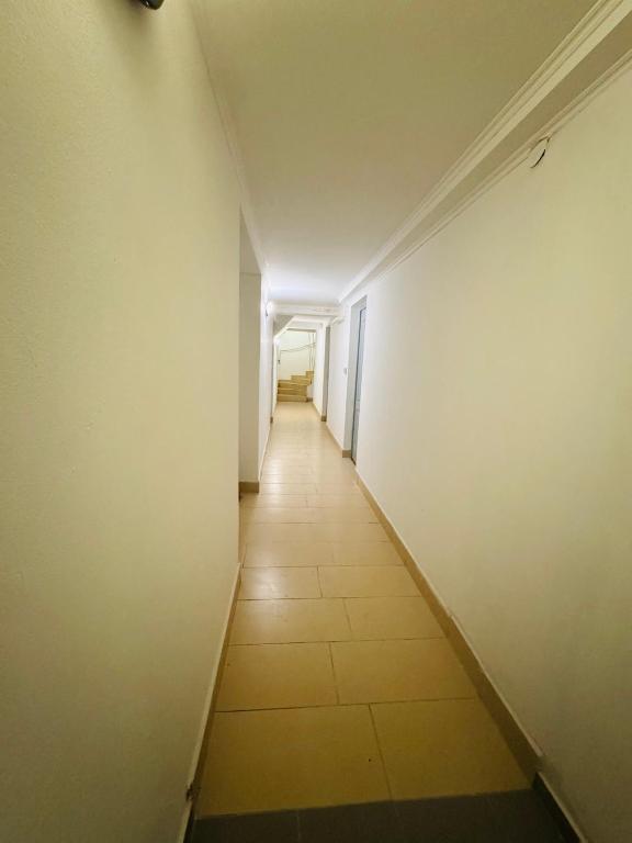 a long hallway with a white wall and a tile floor at Opera Stay in Budapest