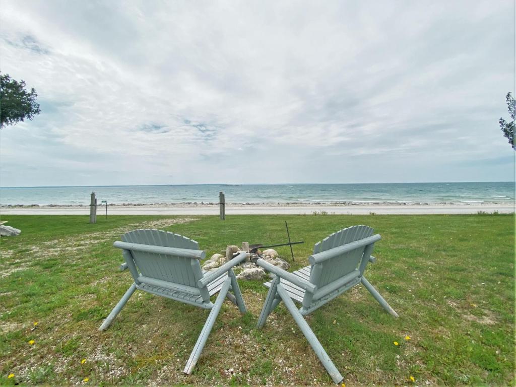 two chairs sitting on the grass near the beach at Serendipity in Saint Ignace