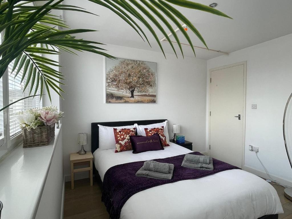 a bedroom with a bed and a palm tree at Modern Apartment overlooking Andover High Street in Andover