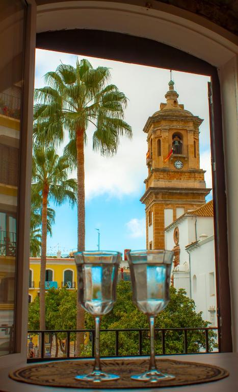 two wine glasses sitting on a table with a clock tower at Suites Plaza Alta in Algeciras