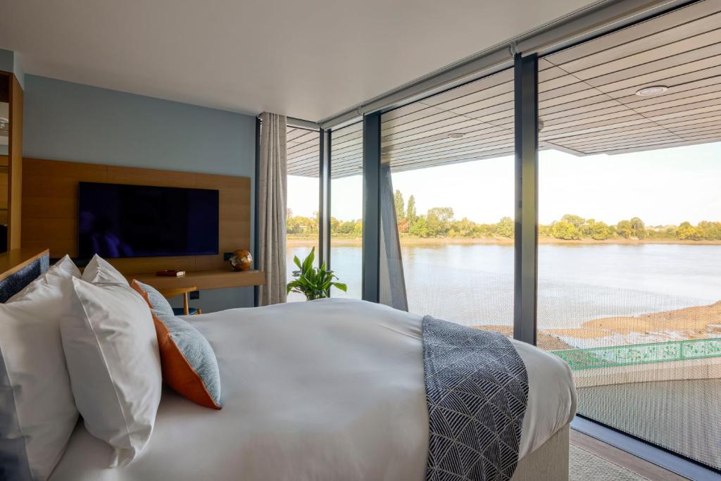 a bedroom with a large bed with a view of a river at Fulham Pier Hotel in London
