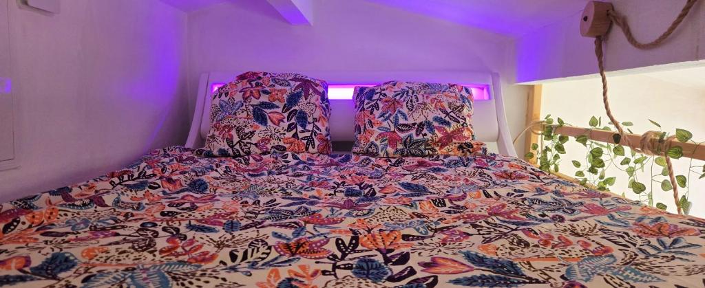 a bed with a colorful comforter in a room at Cœur de Provence in Marignane