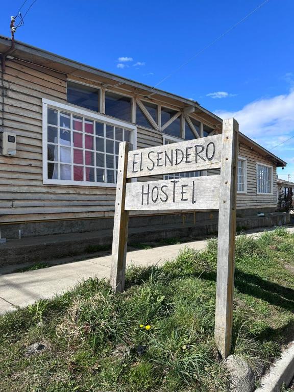 a sign in front of a house with a building at El Sendero in Puerto Natales