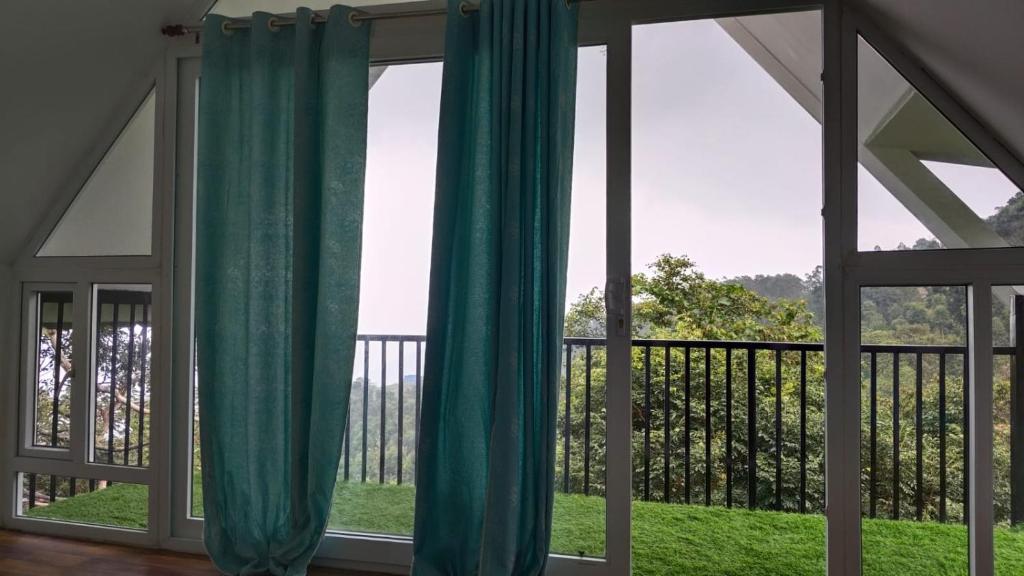 a room with a window with green curtains at Nomadcasa Rooms in Kanthalloor