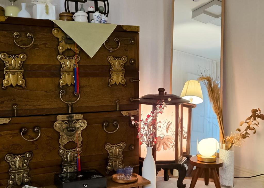 a room with a large wooden chest with a lamp and a table at SarangChae in Busan