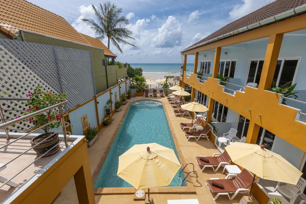 an outdoor swimming pool with umbrellas and the ocean at Kamala Dreams in Kamala Beach