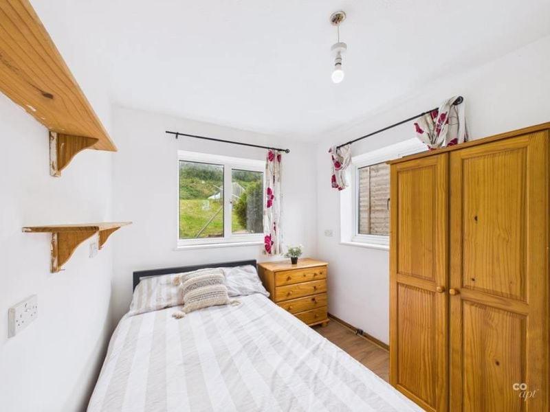 a bedroom with a bed and a dresser and two windows at Spacious 5 BR Brighton Home with Parking in Brighton & Hove