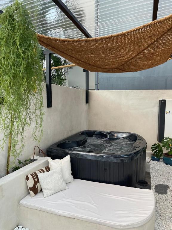 a hammock on a patio with a hot tub at Le Veloutier by Hestia LCD, 1 chbre avec SPA privé in Bois de Nèfles