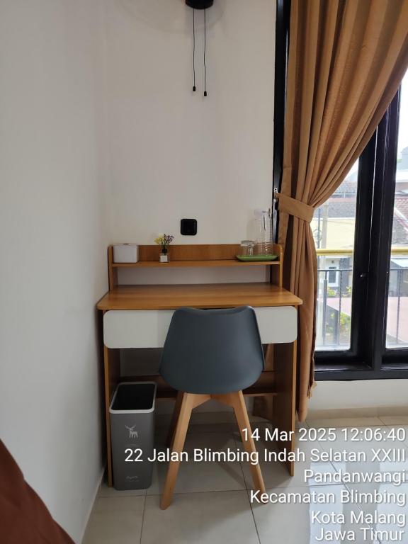 a desk with a chair in a room with a window at Neomi Homestay Malang in Wendit