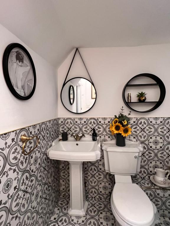 a bathroom with a sink and a toilet and mirrors at Sea Spray Victorian Apartment in St. Leonards