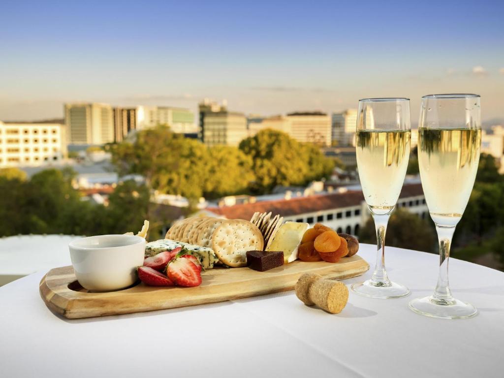 una bandeja de comida y dos copas de vino en Novotel Canberra, en Canberra