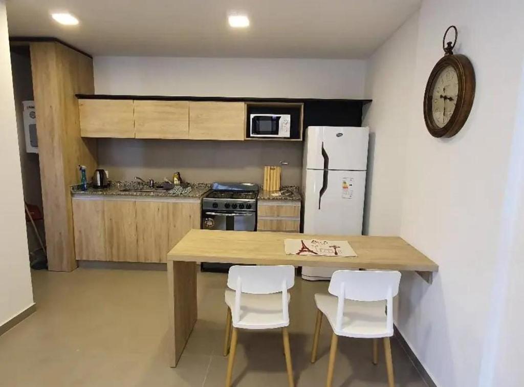 a kitchen with a wooden table and white chairs at Hospedaje Molina in Buenos Aires
