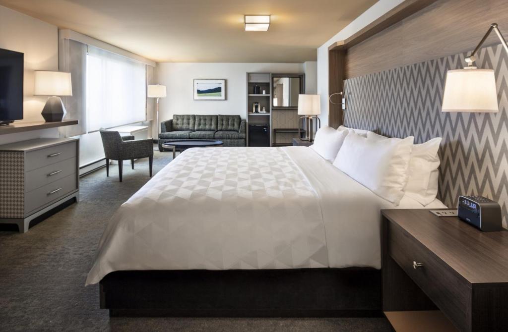 a hotel room with a large bed and a living room at Holiday Inn Montreal Longueuil by IHG in Longueuil