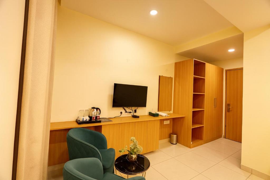 a room with a tv and a chair and a table at The Blue Vista in Greater Noida