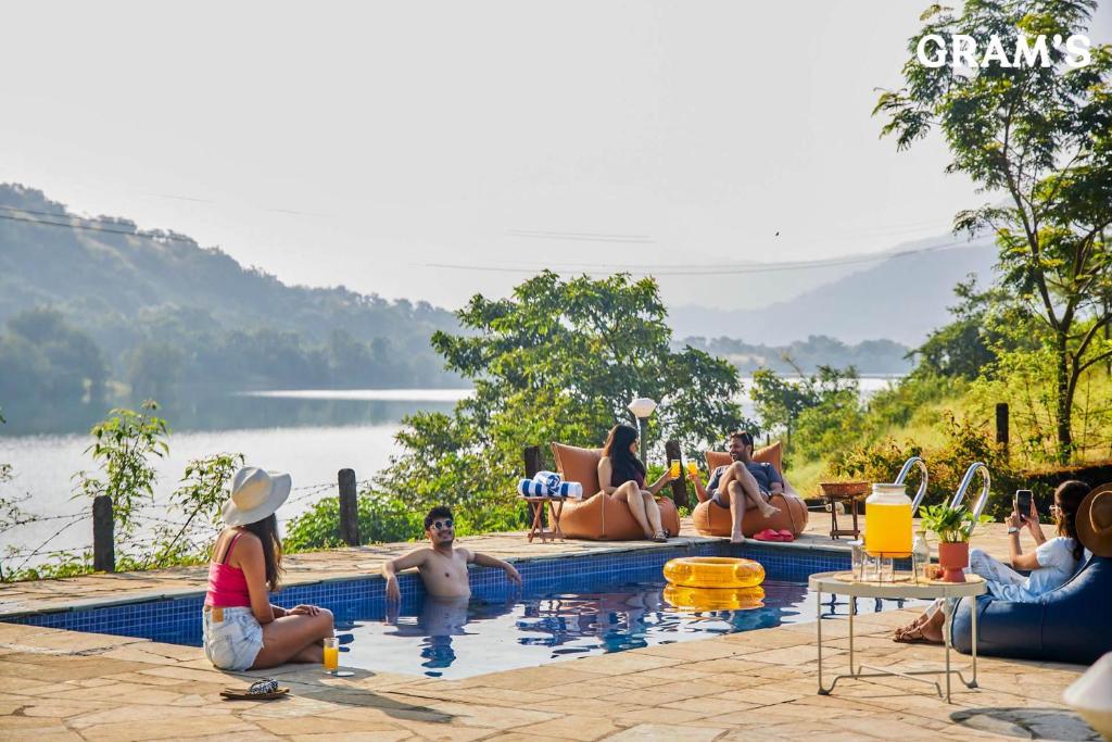 a group of people sitting around a swimming pool at Gram's at Shivom, Pawna Lake in Lonavala
