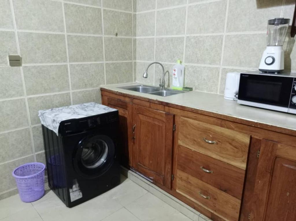 a kitchen with a sink and a washing machine at 1 chambre salon climatisé in Cotonou
