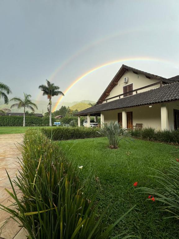 a rainbow over a house with a yard at Recanto Vale Minã in Lavrinhas