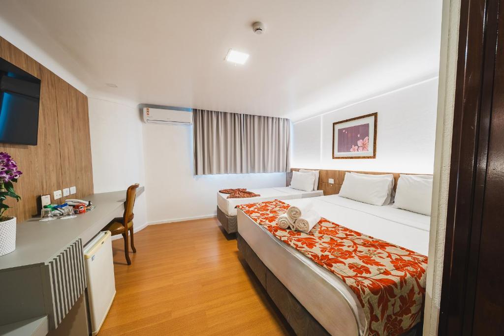 a hotel room with two beds and a desk at Hotel Dan Inn Curitiba Centro By Nacional Inn in Curitiba