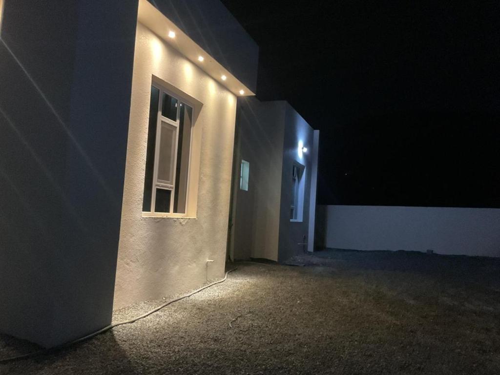 a white building with a window and lights on it at إطلالة غروب الشمس in Misfāh