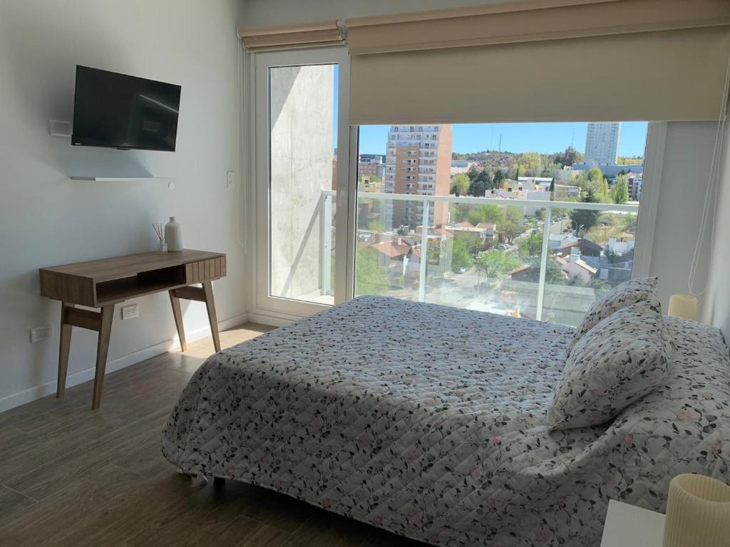 Un dormitorio con una cama y un escritorio y una ventana. en M Tower, en Neuquén