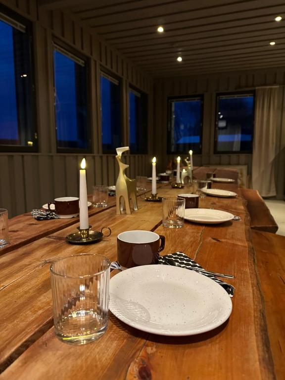 uma longa mesa de madeira com pratos e velas em Shaman Village - Resort & Glass Igloos em Rovaniemi
